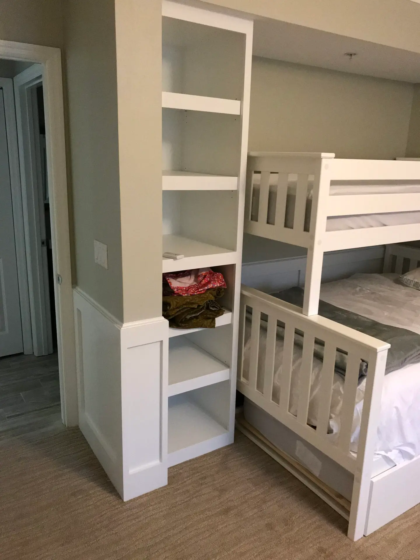 Custom bunk beds with built-in shelving and a paneled accent wall