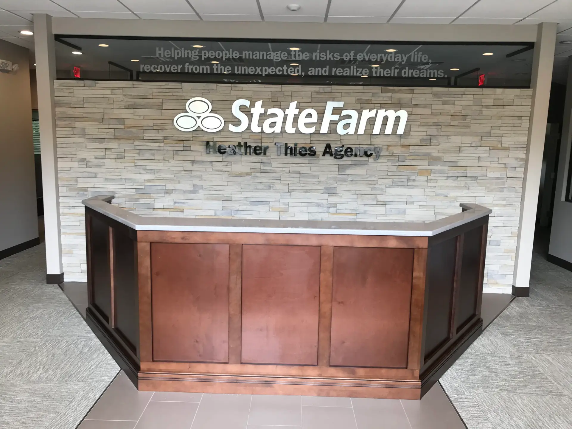 Finished reception desk and stone feature wall with dimensional signage in a completed office buildout