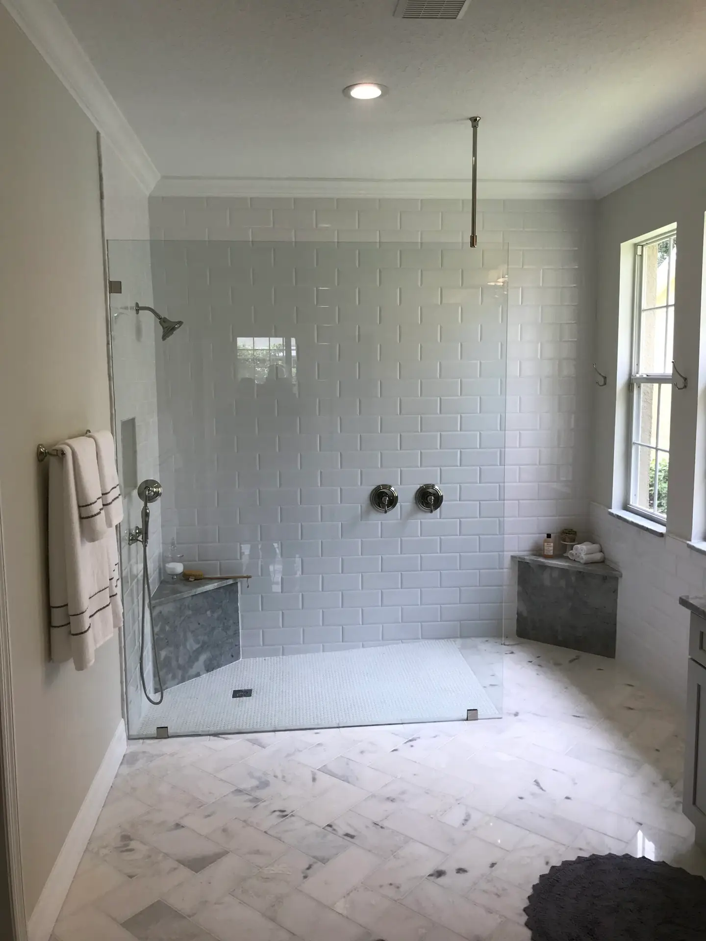 Curbless roll-in shower with a level threshold and full-width glass panel