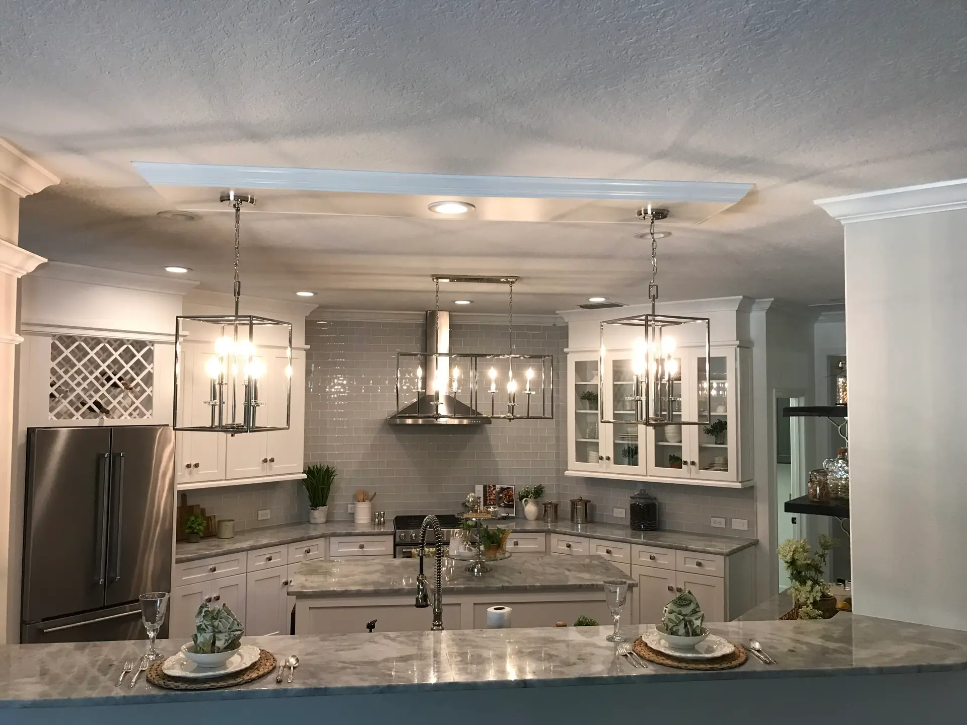 Finished kitchen with a marble-topped island, glass-front upper cabinetry and stainless appliances