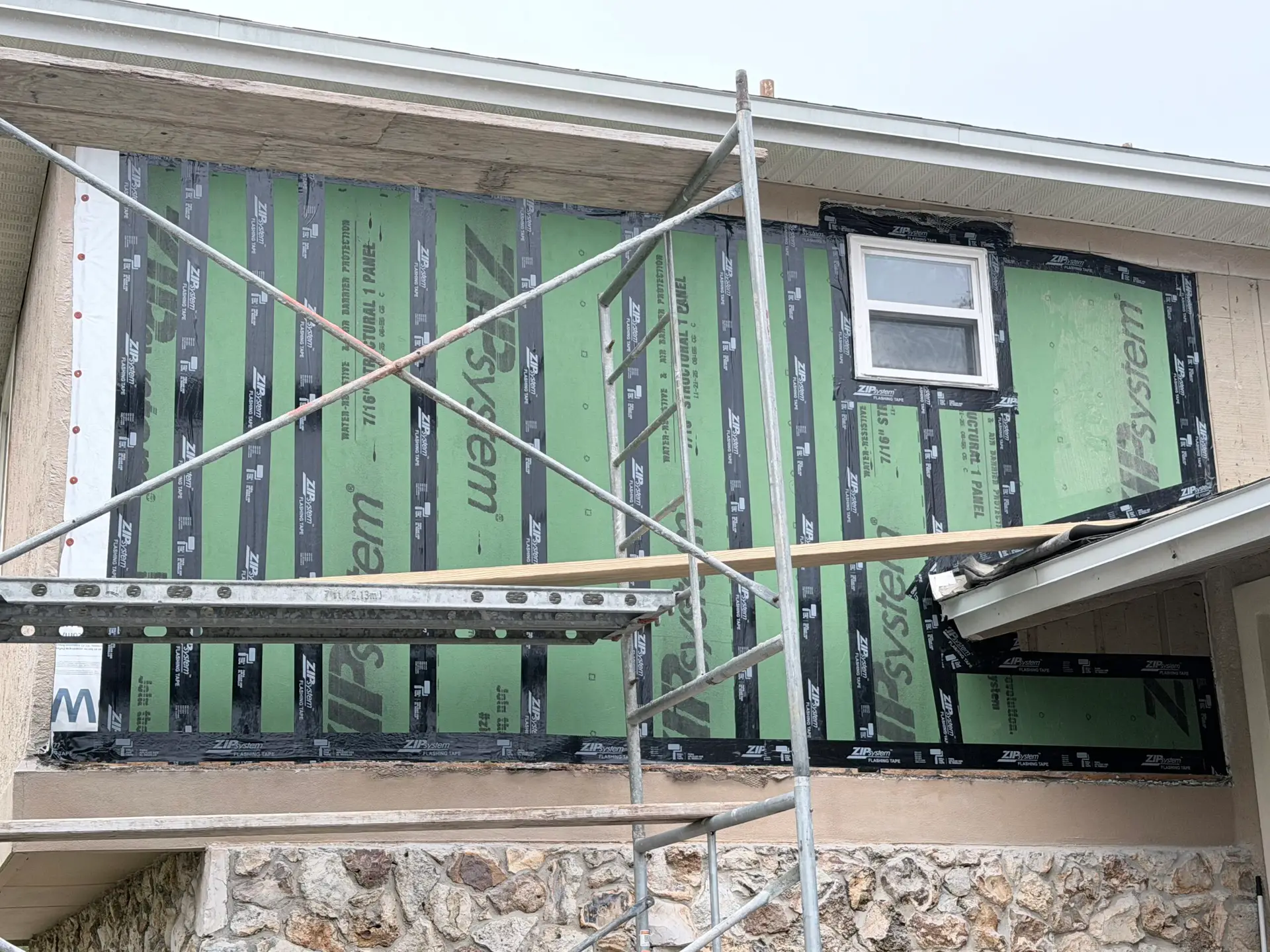 Exterior wall sheathing and weather barrier with scaffolding during a renovation