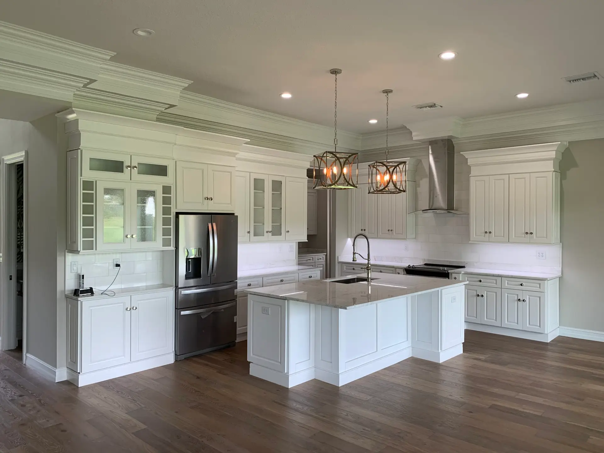 Finished white kitchen with a quartz island, pendant lighting and full-height cabinetry
