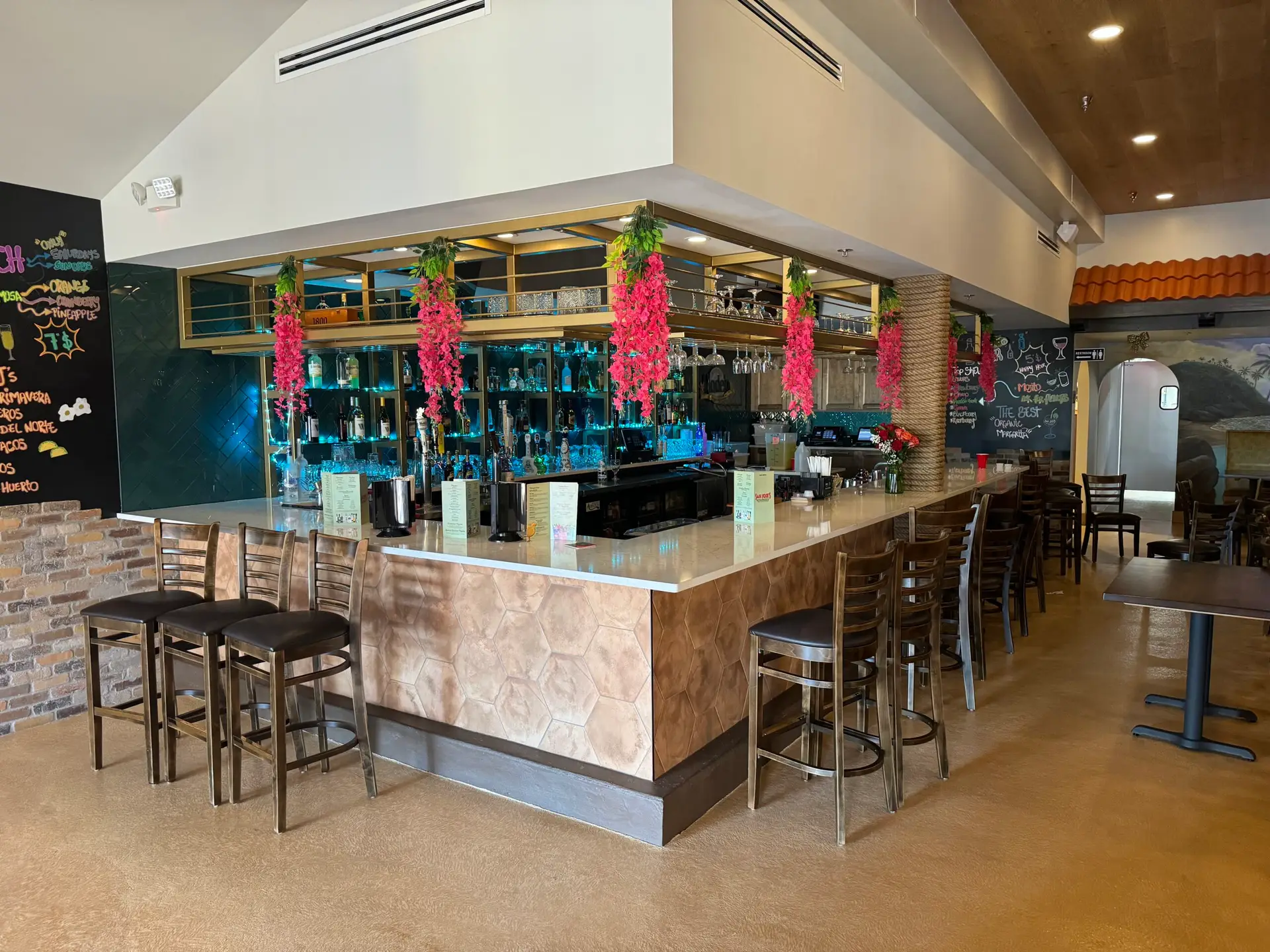 Finished bar with a stone-clad front, counter seating and overhead glassware storage