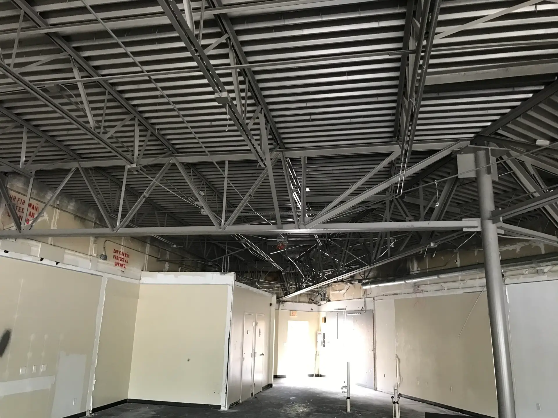 Commercial shell space with exposed bar joists and partial partition framing before finishes