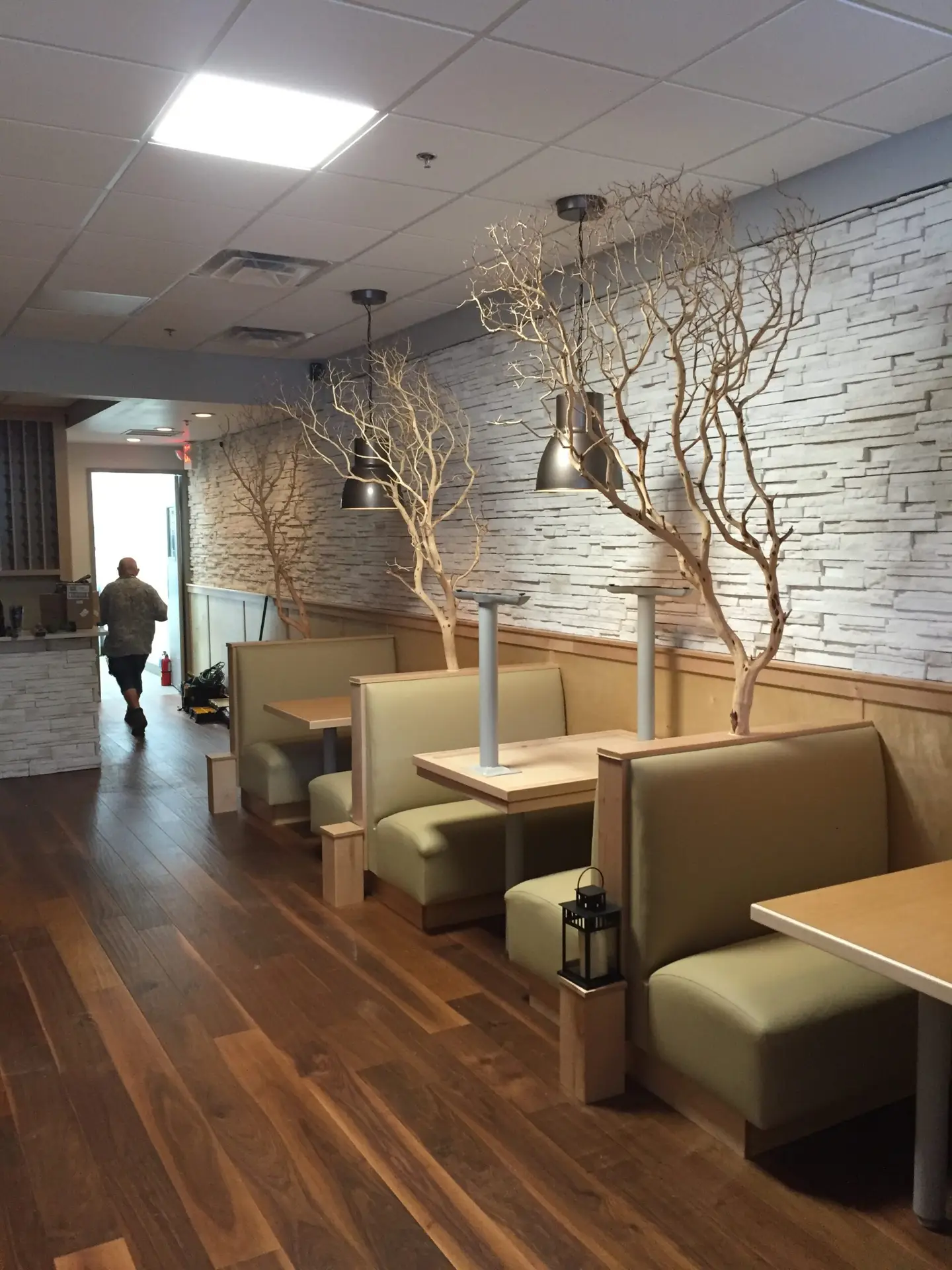 Restaurant dining room with upholstered booths, pendant lighting and a stone accent wall
