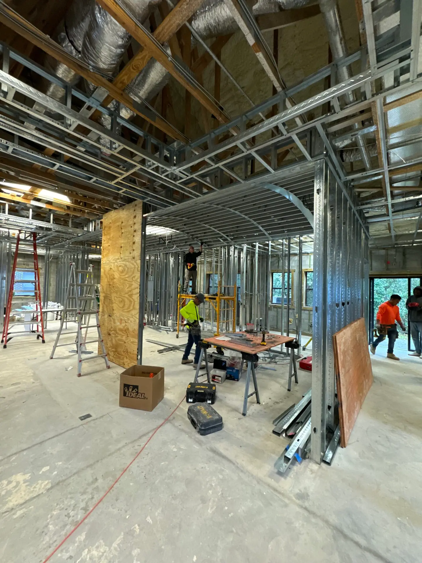 Interior framing and overhead rough-in in progress with crews on site