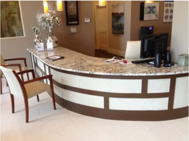 Curved reception and check-in desk with a granite countertop in a finished professional office